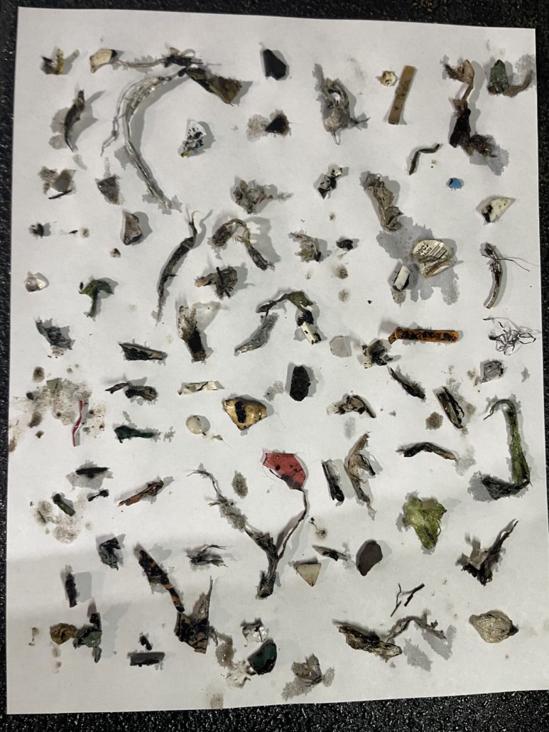 Dozens of glass and plastic contaminant fragments laid out on white paper